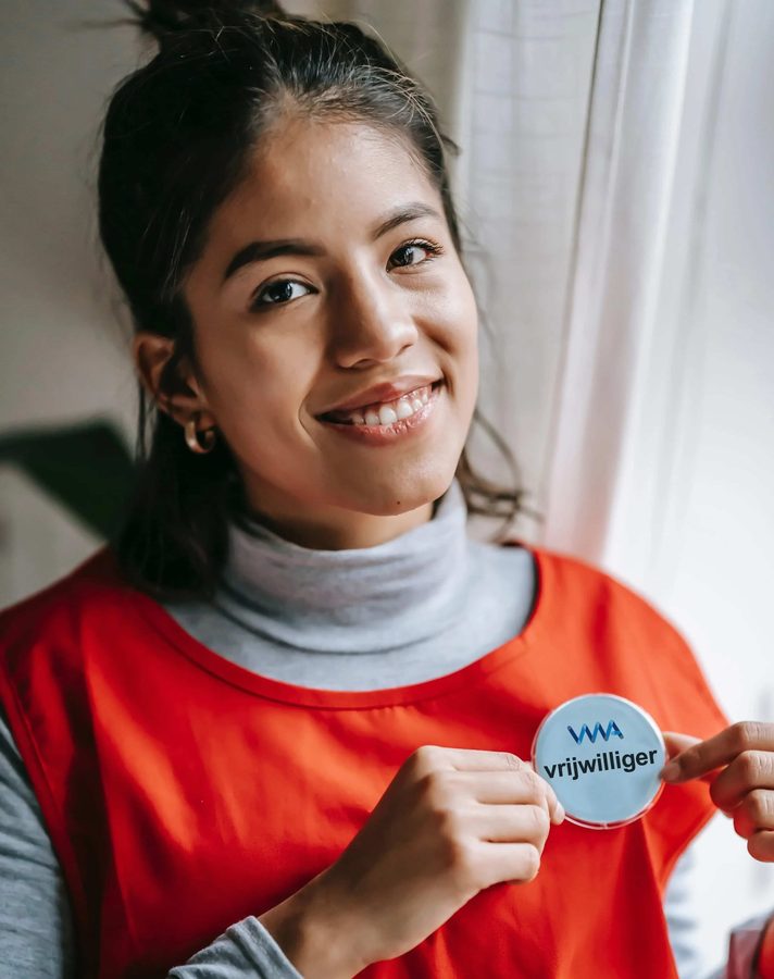 Een vrijwilliger van SVWA laat trots haar vrijwilligersbadge zien